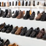 Diversity of leather and textile boots on shelves in salesroom of shoeshop.
