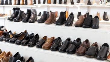 Diversity of leather and textile boots on shelves in salesroom of shoeshop.