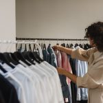 woman in beige long sleeve choosing clothes from other clothes