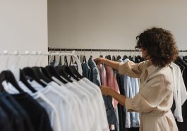 woman in beige long sleeve choosing clothes from other clothes