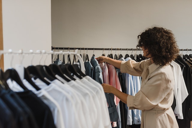 woman in beige long sleeve choosing clothes from other clothes